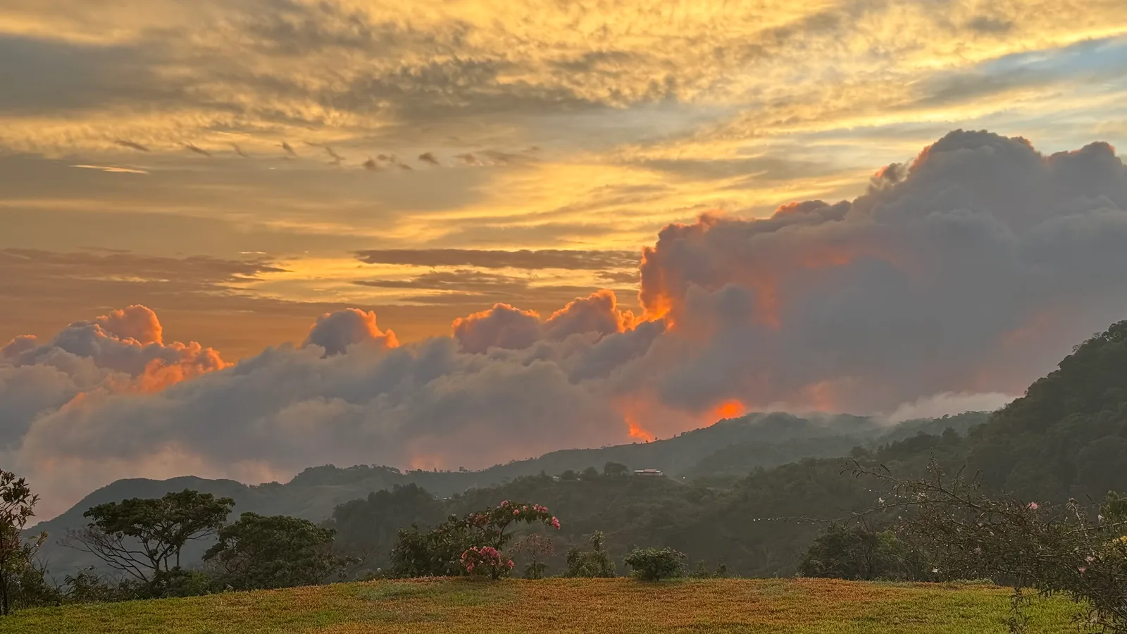 [id: A panoramic view of mountains and clouds at sunset.]