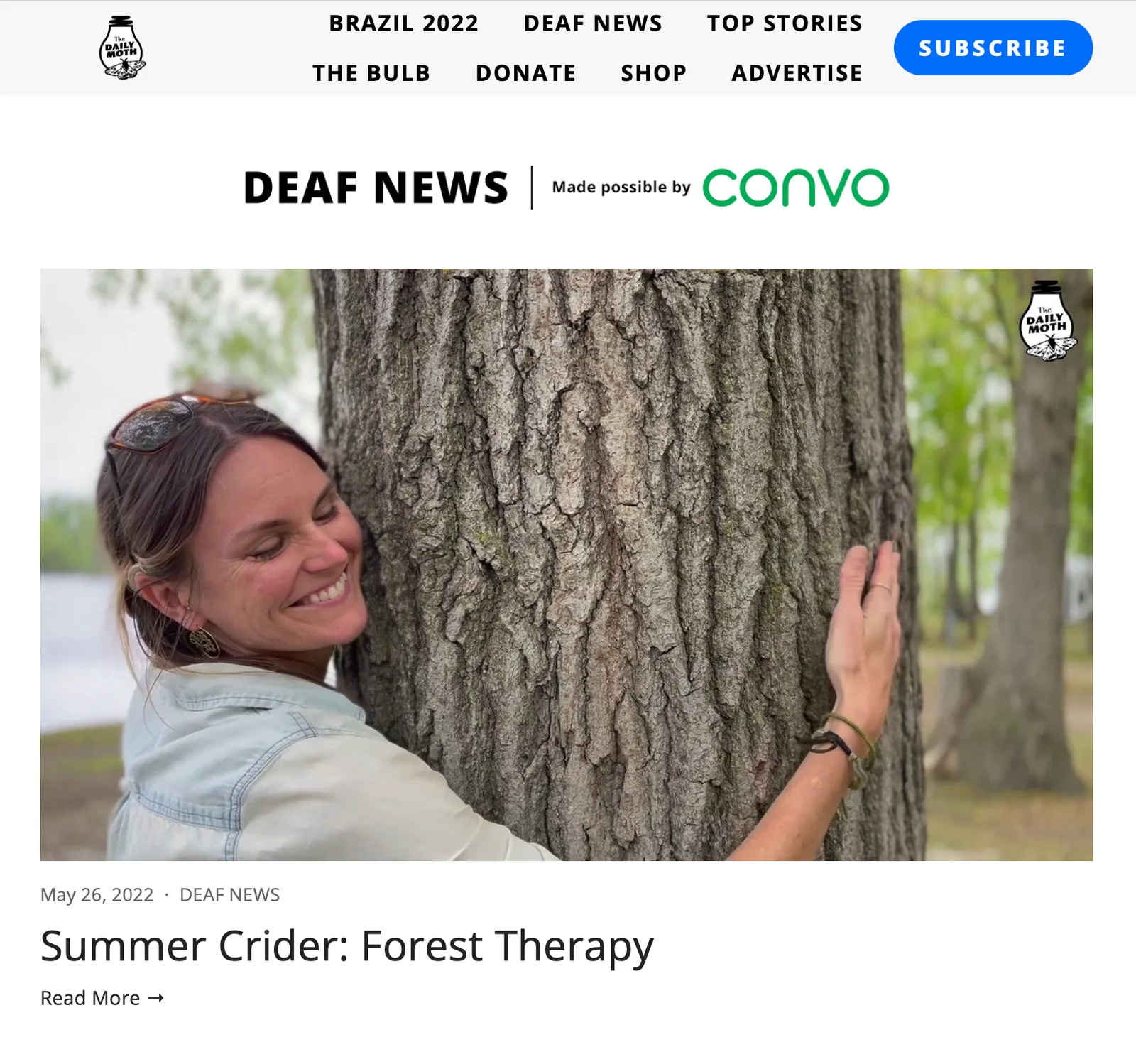 Screenshot of The Daily Moth’s Deaf News page: “Summer Crider: Forest Therapy,” May 26, 2022, with a photo of a woman smiling as she hugs a tree.
