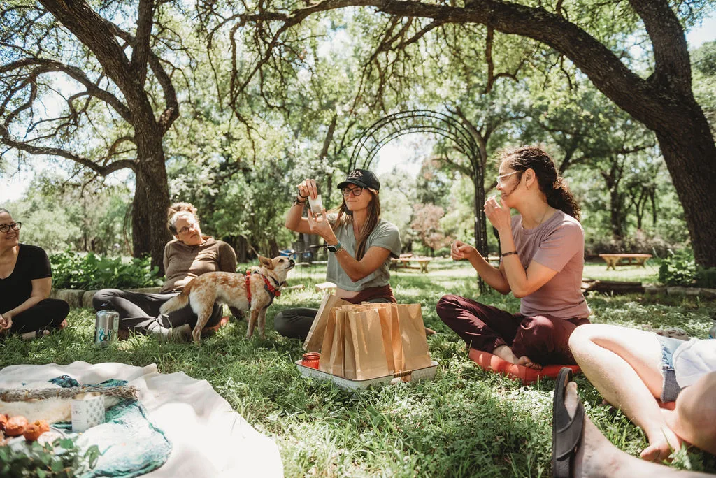 Summer sits in a circle teaches how to create tea bags from plants.